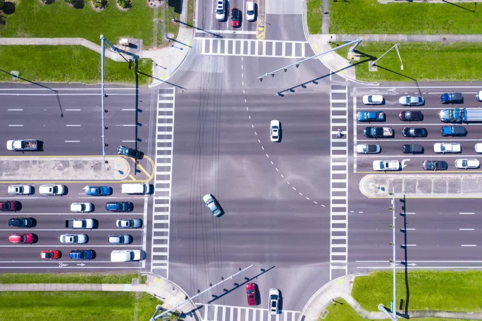 Bird-s eye view of multi-lane road intersection with medians and crosswalks.